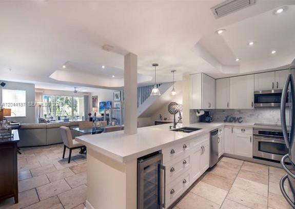 A kitchen with white cabinets and a stone-topped island overlooks an open-concept living area — 7622 SW 102nd St # 120, Pinecrest FL 33156, PINECREST, FL