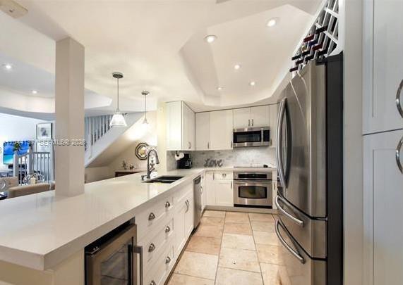 A modern kitchen features white cabinetry, stainless steel appliances, a breakfast bar, and tile flooring — 7622 SW 102nd St # 120, Pinecrest FL 33156, PINECREST, FL