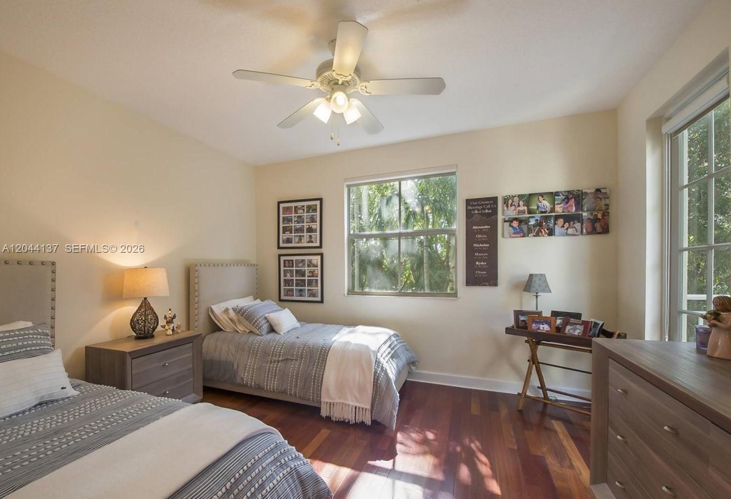 A bedroom features two twin beds, dark wood flooring, a ceiling fan, and a window — 7622 SW 102nd St # 120, Pinecrest FL 33156, PINECREST, FL