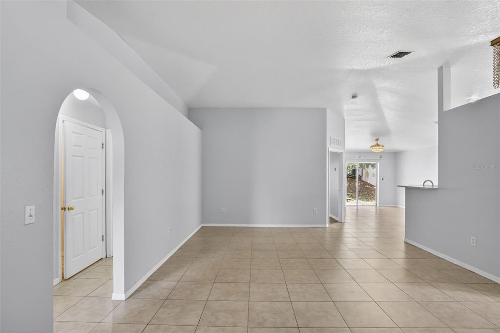 An empty room with light gray walls, tile flooring, and an arched doorway — 432 BARLYN AVENUE, HAINES CITY, FL