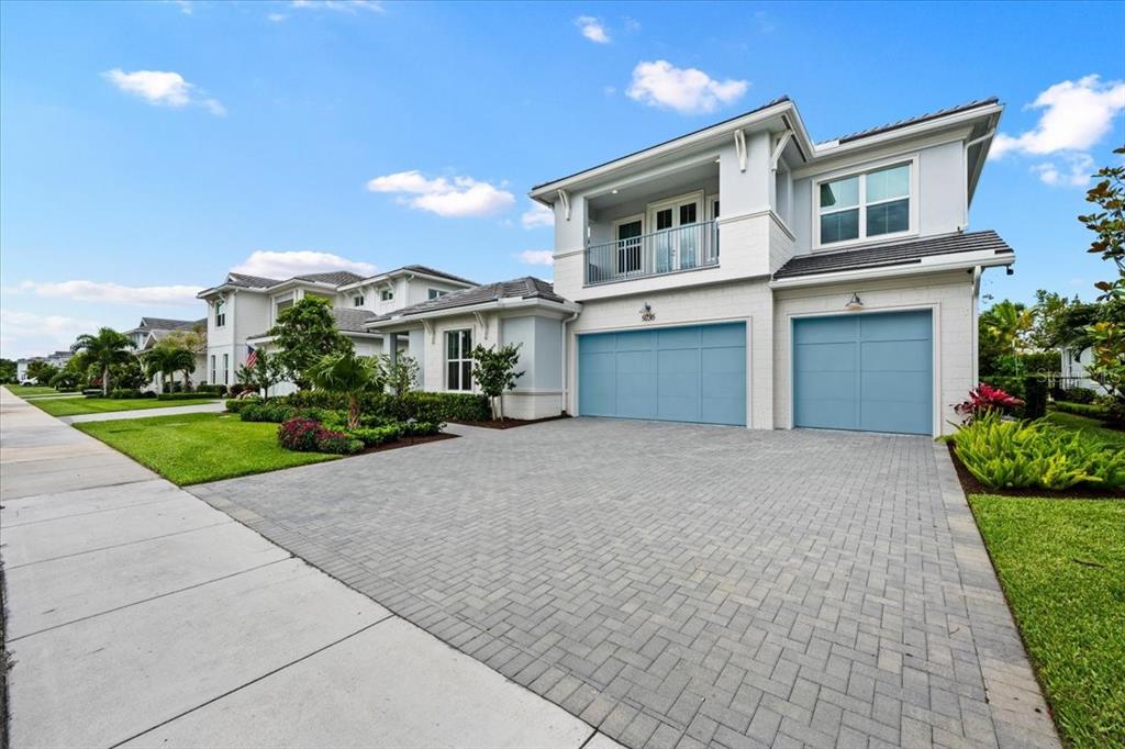 A two-story house with a paved driveway, blue garage doors, and a second-floor balcony — 9236 CRESTVIEW CIRCLE, PALM BEACH GARDENS, FL