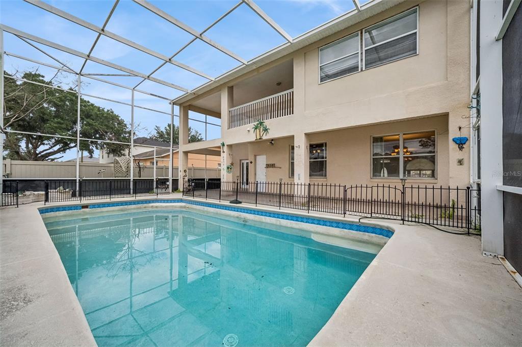 A swimming pool with a screen enclosure sits in the backyard of a two-story house — 106 CASTLEFORD WAY, KISSIMMEE, FL