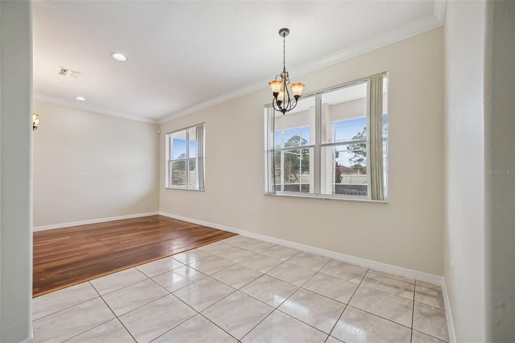 A dining area features a tile floor, a chandelier, and an adjacent wood-floored living space — 106 CASTLEFORD WAY, KISSIMMEE, FL