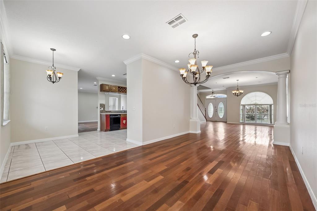 A dining area with tiled floors transitions into a living space with hardwood flooring — 106 CASTLEFORD WAY, KISSIMMEE, FL