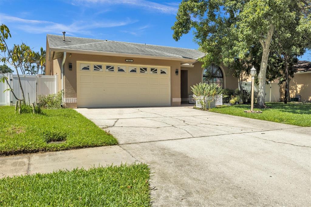 A single-story house with a beige exterior, a two-car garage, and a concrete driveway — 3631 102ND PLACE N, CLEARWATER, FL