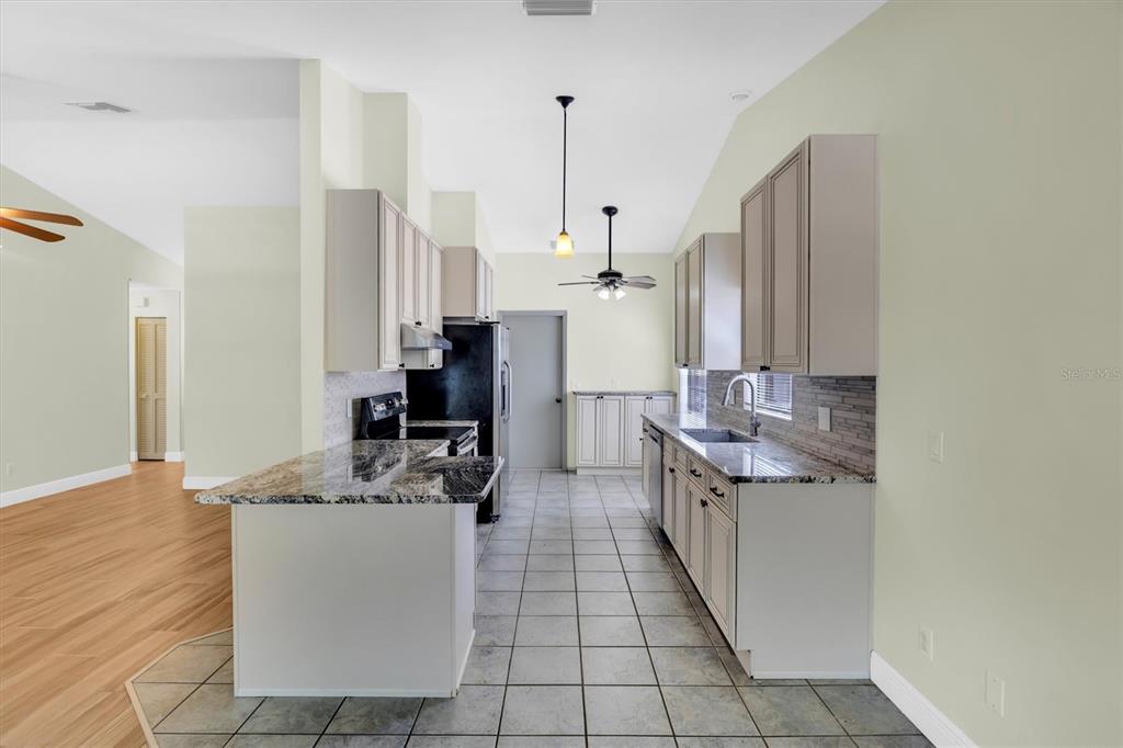 A kitchen with light-colored cabinets, granite countertops, tile flooring, and stainless steel appliances — 3631 102ND PLACE N, CLEARWATER, FL