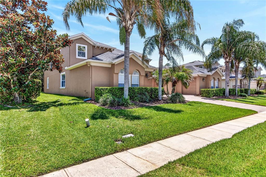 A two-story tan house with a palm tree in the front yard and a sidewalk — 3198 HEIRLOOM ROSE PLACE, OVIEDO, FL