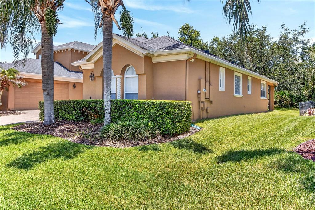 A tan stucco house with a side-entry garage and palm trees in the front yard — 3198 HEIRLOOM ROSE PLACE, OVIEDO, FL