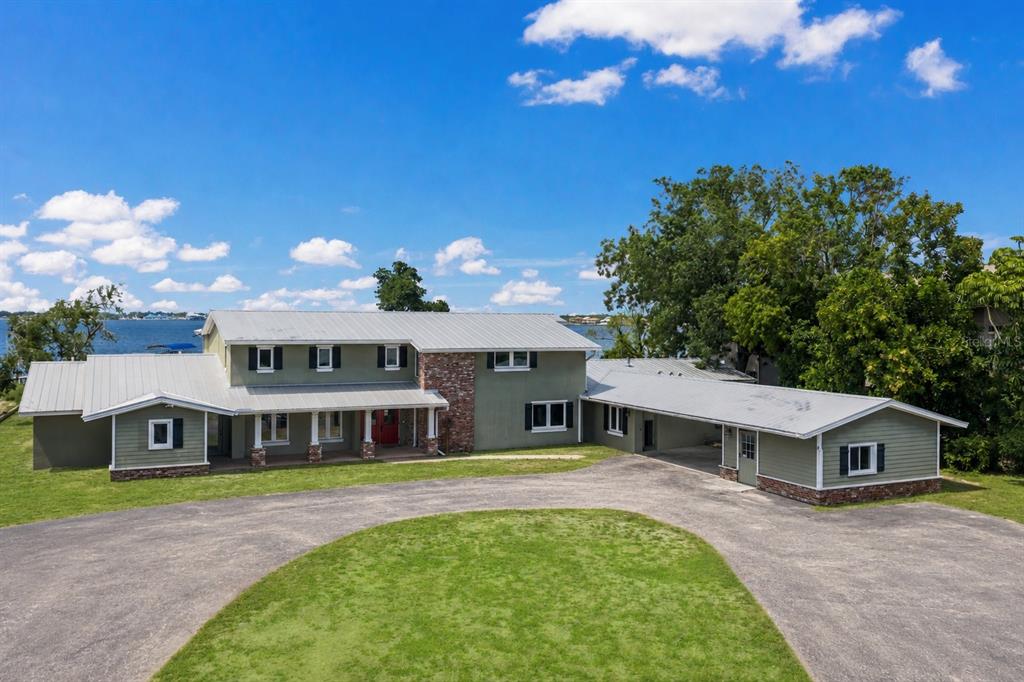 A two-story green house with a metal roof and a large circular gravel driveway — 4900 RIVERVIEW BOULEVARD, BRADENTON, FL
