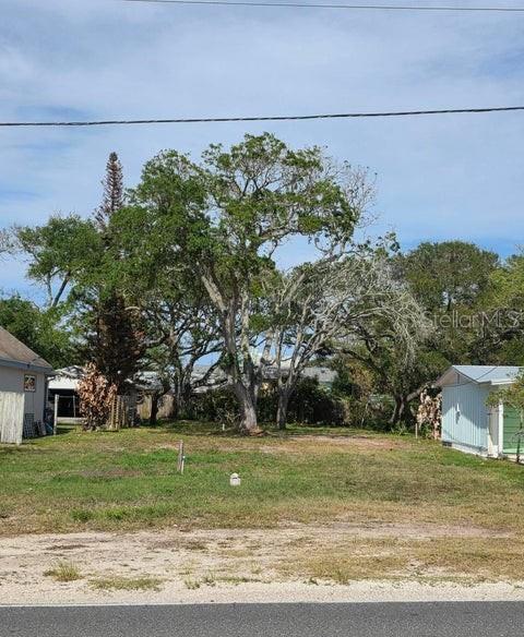 A vacant residential lot features several large mature trees and neighboring houses on both sides — 2803 SAXON DRIVE, NEW SMYRNA BEACH, FL