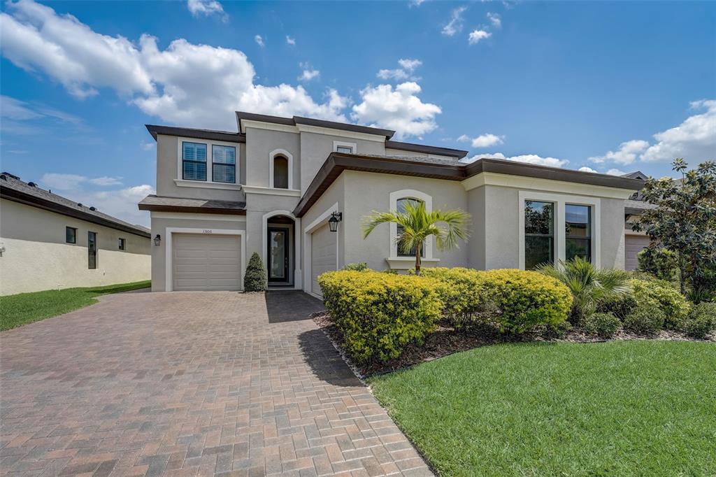A two-story suburban house with a paved driveway, tan stucco exterior, and a small palm tree — 13106 FOXTAIL FERN DRIVE, RIVERVIEW, FL