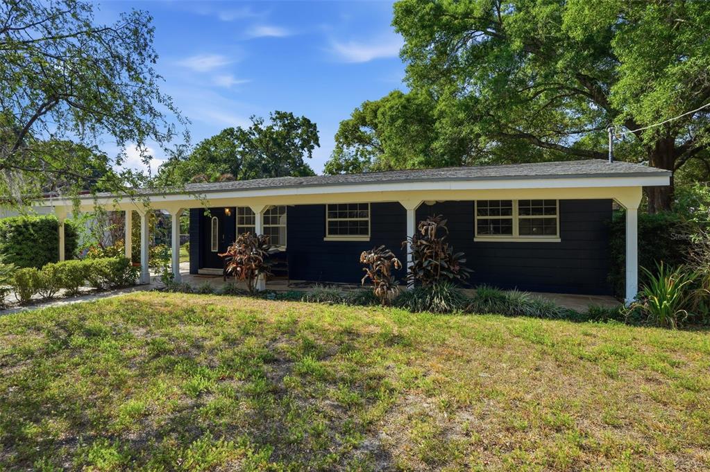 A single-story house with dark blue siding and a covered front porch under large trees — 1708 POND LAKE DRIVE, TAMPA, FL