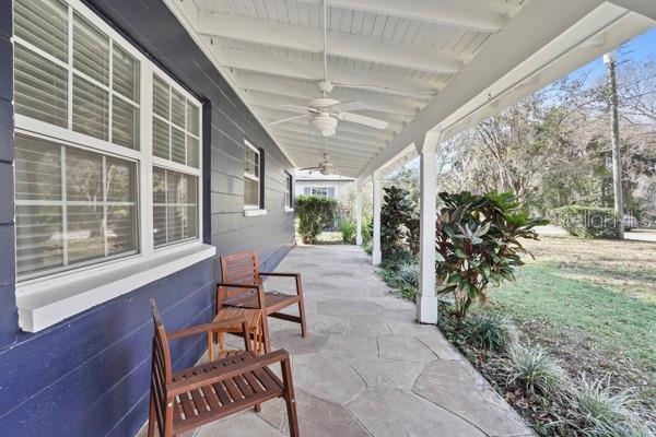 A covered porch with stone flooring, two wooden chairs, and a ceiling fan — 1708 POND LAKE DRIVE, TAMPA, FL