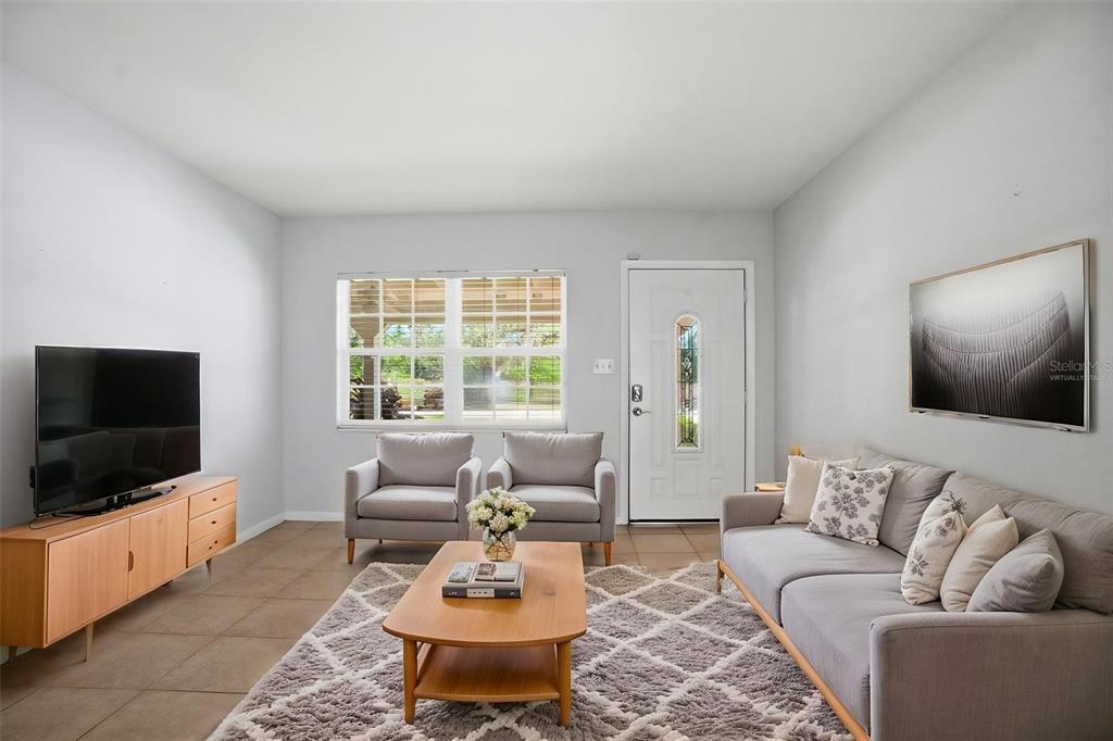 A living room features a grey sofa, two armchairs, a television, and a coffee table — 1708 POND LAKE DRIVE, TAMPA, FL