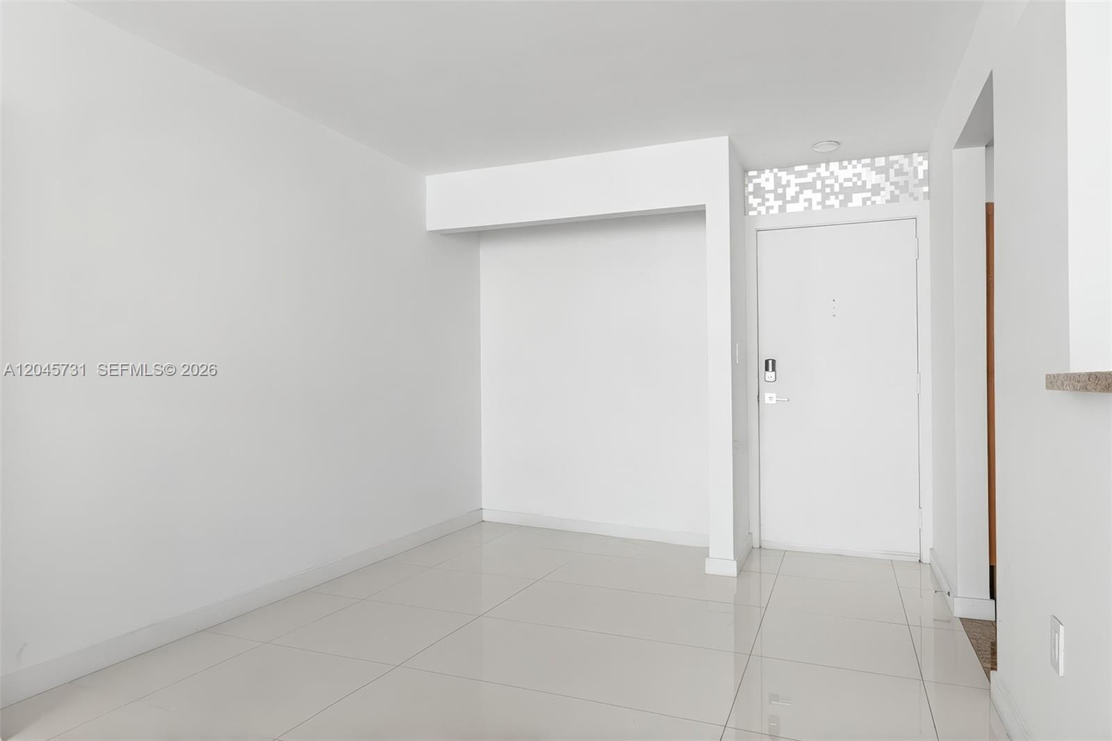 A minimalist room features white walls, light-colored tile flooring, and a white entry door — 1775 Washington Ave # 14F, Miami Beach FL 33139, MIAMI BEACH, FL