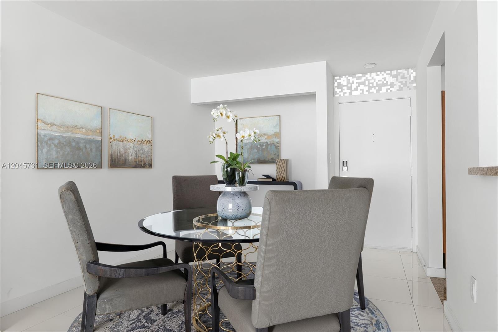 A dining area features a glass-topped table, four gray chairs, and abstract wall art — 1775 Washington Ave # 14F, Miami Beach FL 33139, MIAMI BEACH, FL