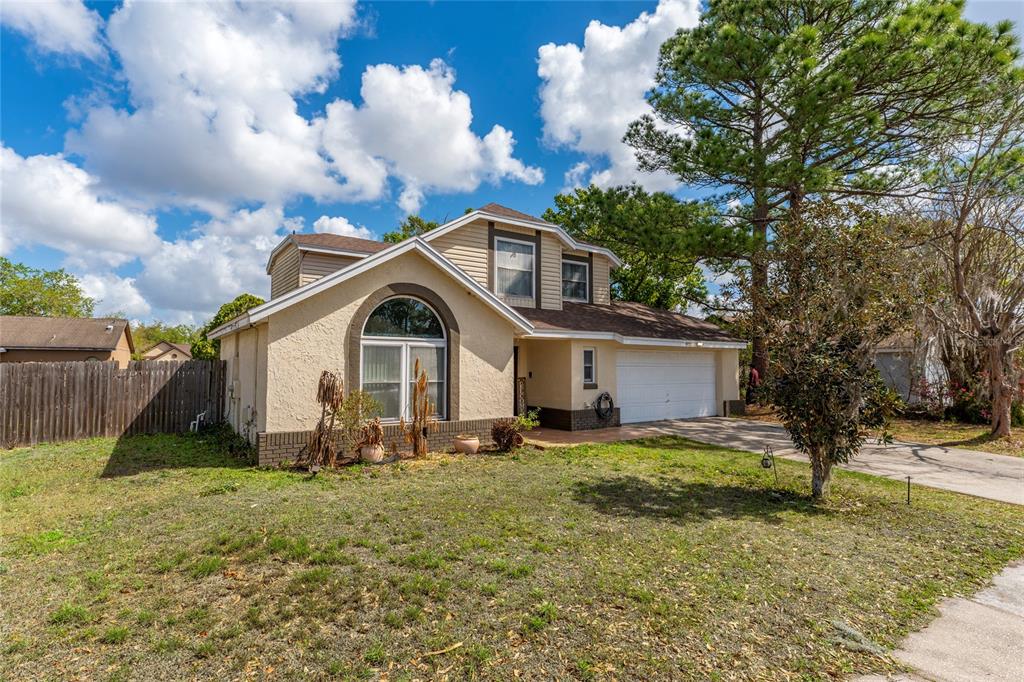 A two-story house with a beige stucco exterior, arched window, and attached two-car garage — 8713 CATBRIAR BAY WAY, ORLANDO, FL
