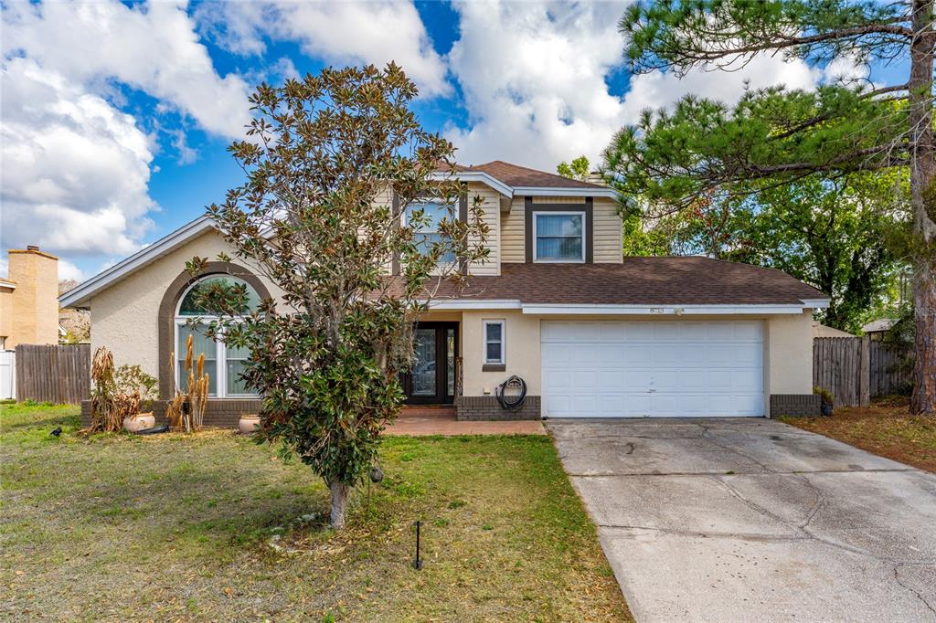 A two-story suburban house features a white garage, arched window, and a front yard tree — 8713 CATBRIAR BAY WAY, ORLANDO, FL