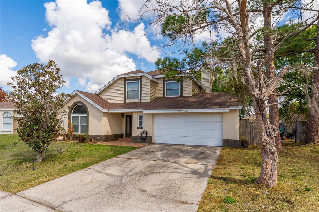 A two-story suburban house with a beige stucco and siding exterior and a two-car garage — 8713 CATBRIAR BAY WAY, ORLANDO, FL
