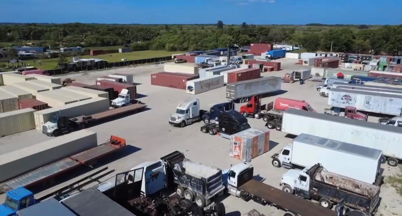 An aerial view shows a large industrial storage yard filled with shipping containers and semi-trucks — 12485 SW 197th Avenue, Miami FL 33196, MIAMI, FL