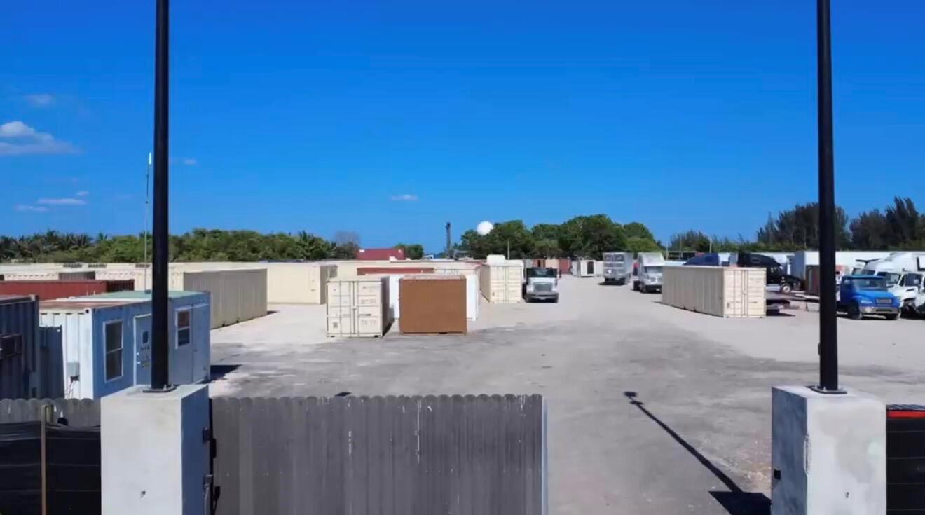 An outdoor storage yard features numerous shipping containers and trucks under a clear blue sky — 12485 SW 197th Avenue, Miami FL 33196, MIAMI, FL