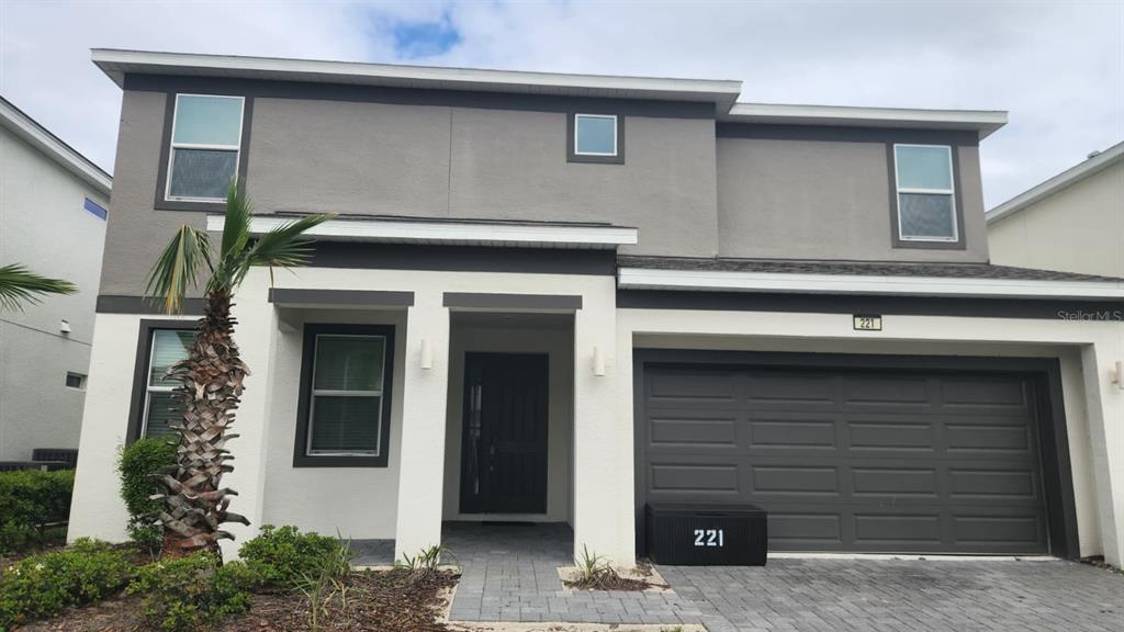 A two-story house with a gray and white exterior, a garage, and a paved walkway — 221 BALLO DRIVE, KISSIMMEE, FL