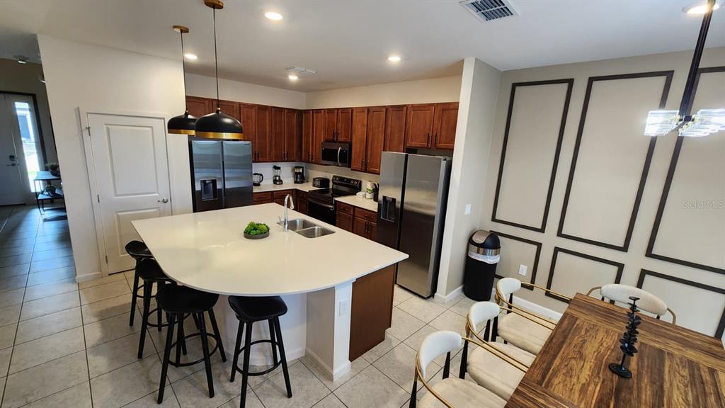 A kitchen features a large white island, stainless steel appliances, and dark wood cabinetry — 221 BALLO DRIVE, KISSIMMEE, FL