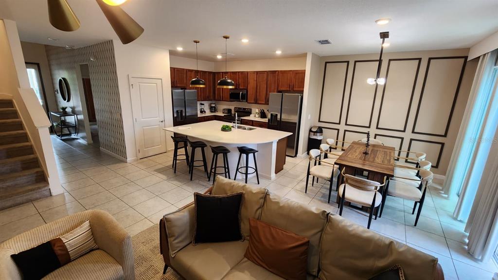 An open-concept kitchen and dining area features dark wood cabinets, a white island, and tile flooring — 221 BALLO DRIVE, KISSIMMEE, FL