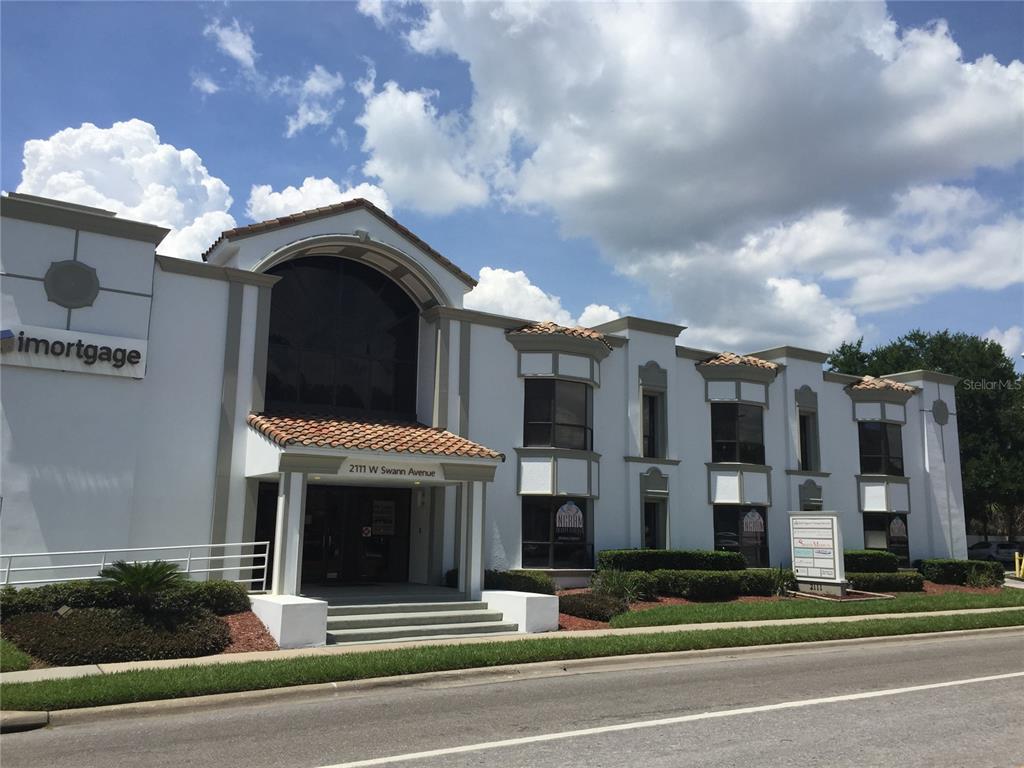 A covered parking garage features concrete pillars, painted yellow curbs, and several parked vehicles — 2111 W SWANN AVENUE, TAMPA, FL