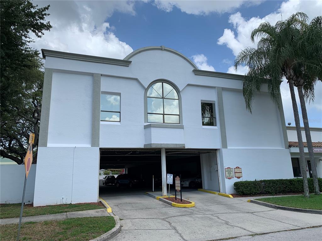 A multi-story tan apartment building features balconies, a tiled roof, and a corner entrance — 2111 W SWANN AVENUE, TAMPA, FL