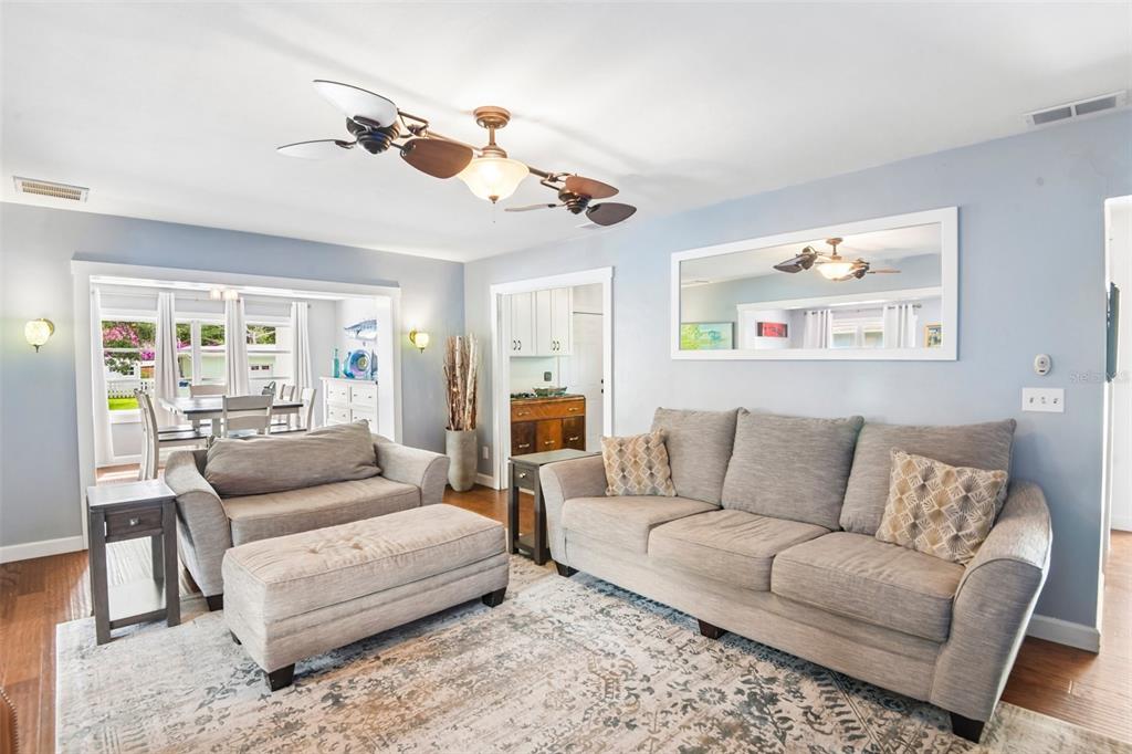 A living room features a gray sofa, matching loveseat, ottoman, area rug, and ceiling fan — 992 HILLWOOD DRIVE, DUNEDIN, FL