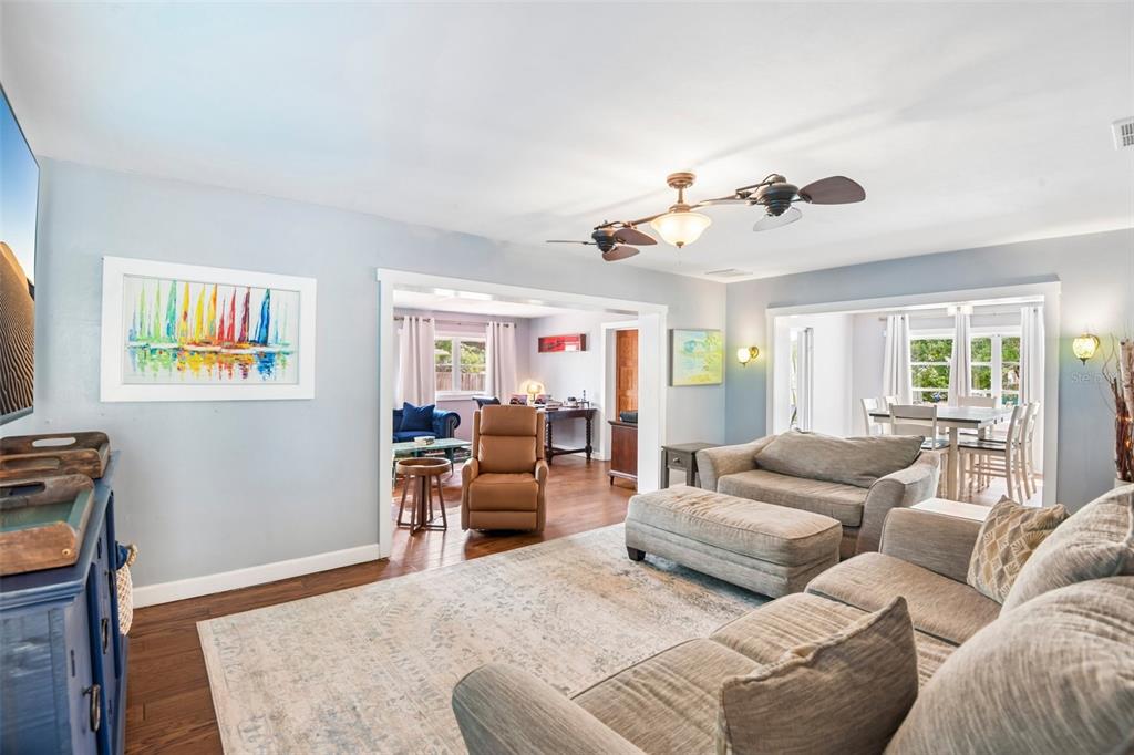 A living room features light blue walls, hardwood floors, a ceiling fan, and neutral furniture — 992 HILLWOOD DRIVE, DUNEDIN, FL