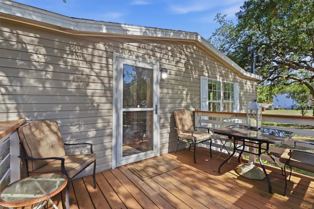 A wooden deck with patio furniture sits in front of a tan vinyl-sided house — 5015 S ORWELL POINT, HOMOSASSA, FL