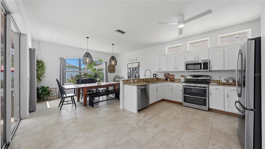 A kitchen and dining area with white cabinets, stainless steel appliances, and tile flooring — 12630 ROCKROSE GLEN, LAKEWOOD RANCH, FL