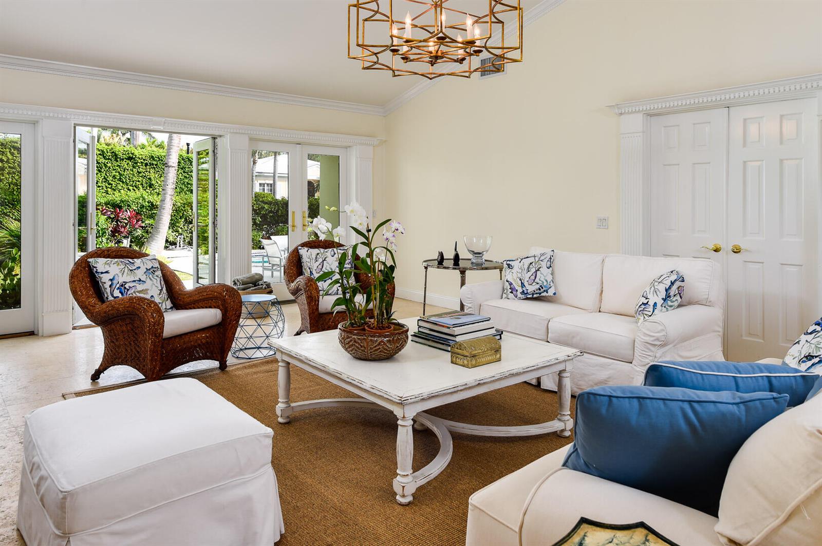 A living room with white sofas, wicker armchairs, a coffee table, and French doors to outdoors — 222 Miraflores Drive, Palm Beach FL 33480, PALM BEACH, FL