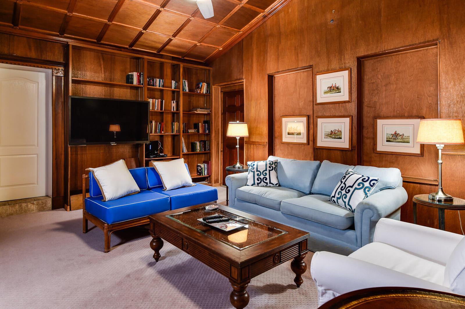 A wood-paneled living room features a blue sofa, a matching loveseat, and a coffee table — 222 Miraflores Drive, Palm Beach FL 33480, PALM BEACH, FL