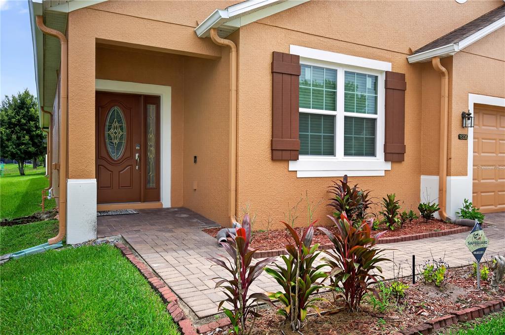 The exterior of a tan stucco house features a brown front door and a shuttered window — 15336 TREVISO STREET, ORLANDO, FL