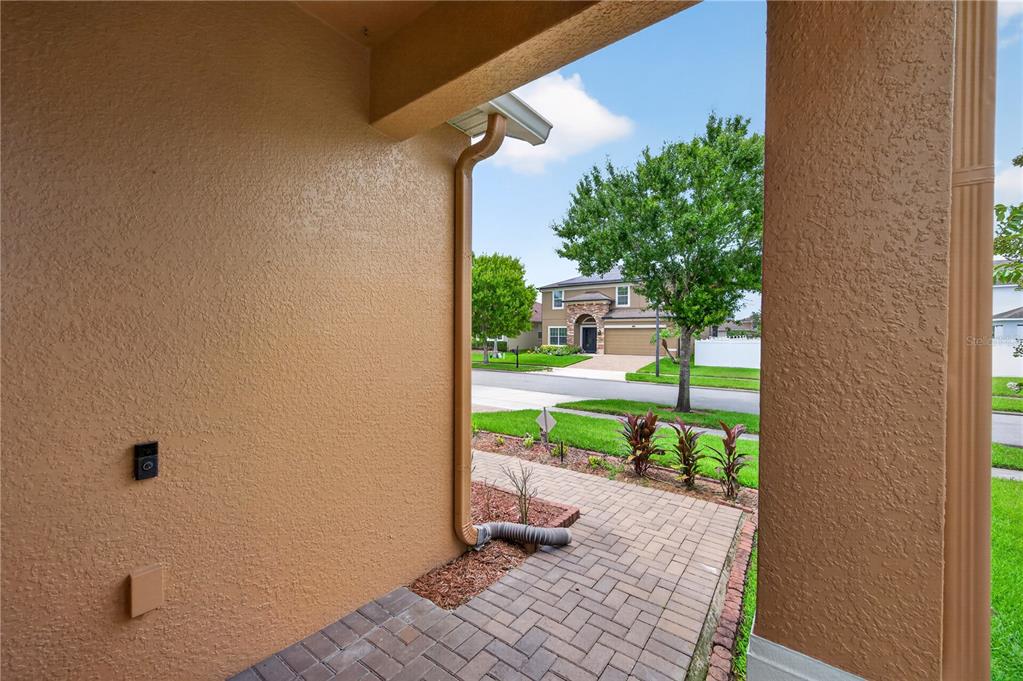 A view from a covered porch looking out toward a suburban street and neighboring house — 15336 TREVISO STREET, ORLANDO, FL