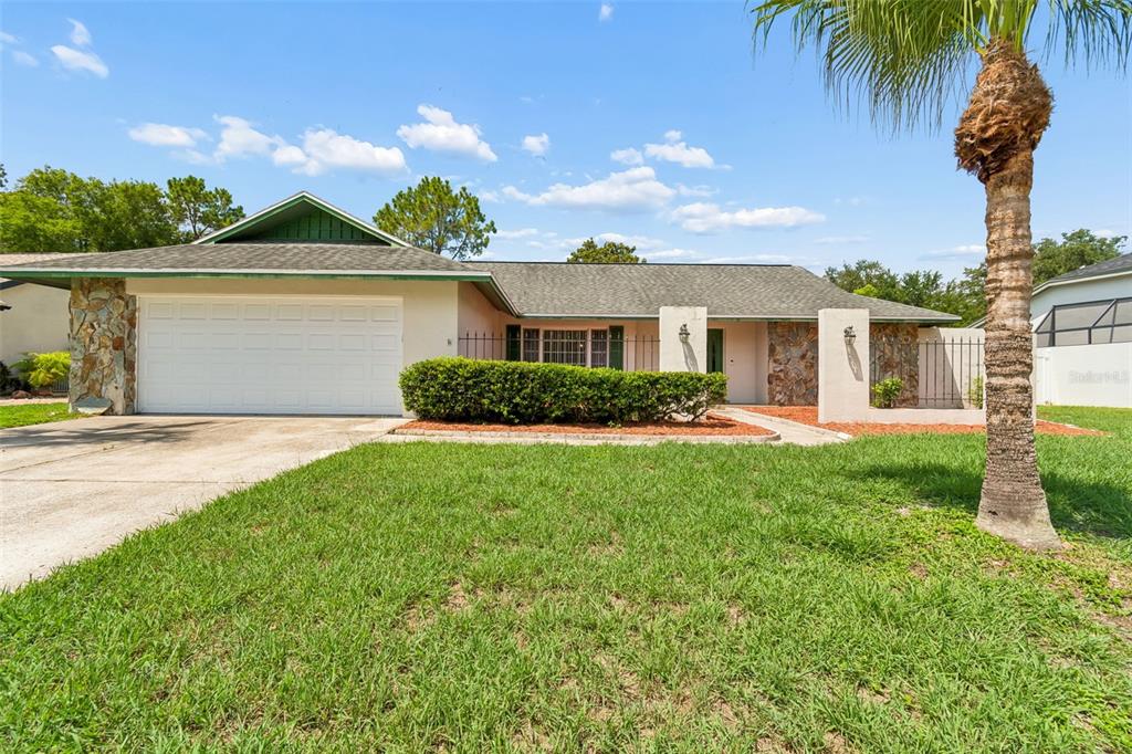 A single-story house with a white garage, stone accents, and a palm tree in front — 9237 PEBBLE CREEK DRIVE, TAMPA, FL