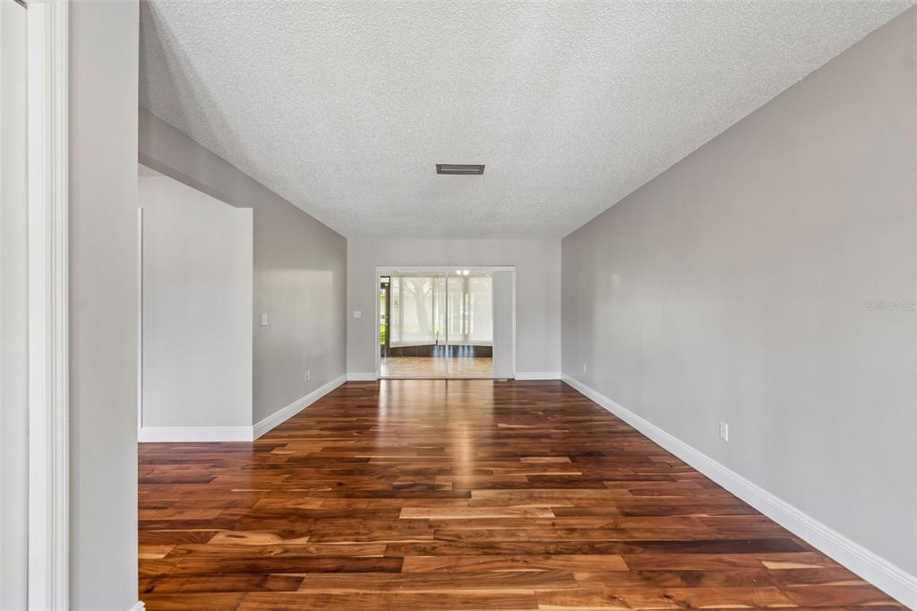 An empty room with gray walls, dark wood flooring, and sliding glass doors to a patio — 9237 PEBBLE CREEK DRIVE, TAMPA, FL