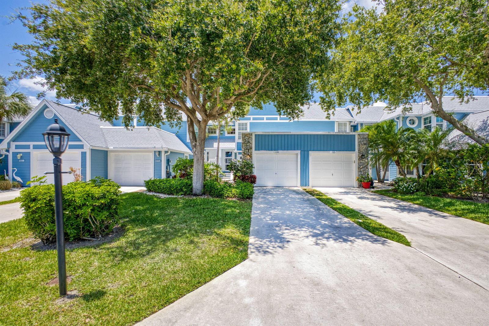 A blue multi-unit residential building with white garage doors and a large front tree — 1106 Ocean Dunes Circle, Jupiter FL 33477, JUPITER, FL
