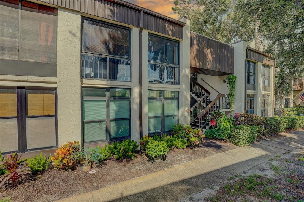 A two-story apartment building exterior with large windows, brown trim, and a concrete walkway — 2400 WINDING CREEK BOULEVARD UNIT 26-203, CLEARWATER, FL