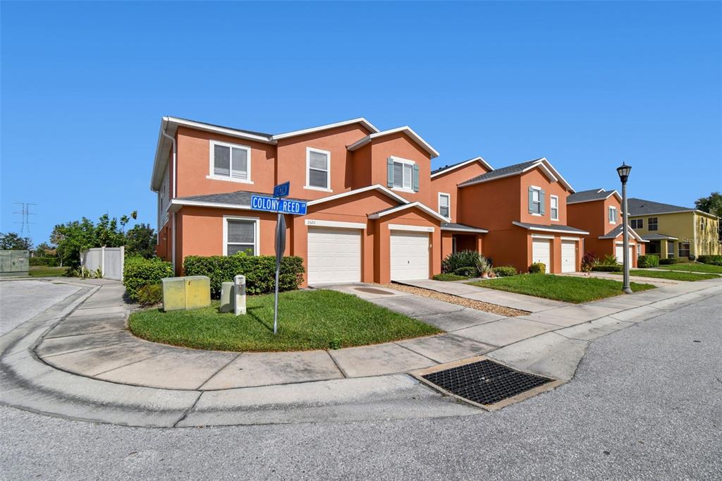 A row of orange two-story townhomes with attached garages sits along a suburban street — 2520 COLONY REED LANE, CLEARWATER, FL