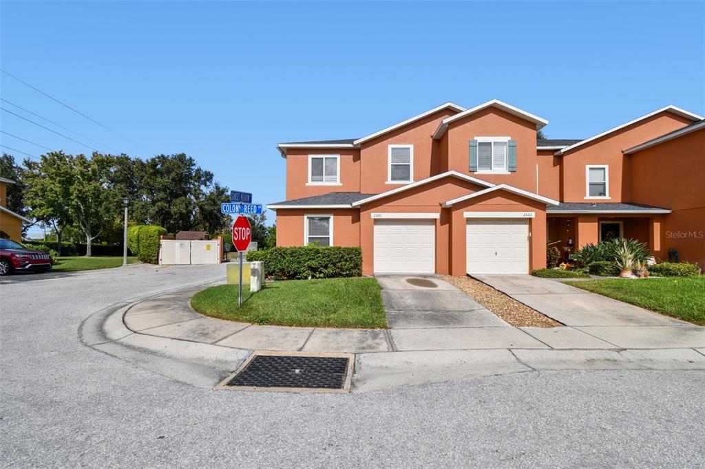 An exterior view of a two-story orange townhouse with two garages and a stop sign — 2520 COLONY REED LANE, CLEARWATER, FL