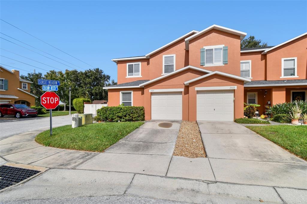 An exterior view of a two-story orange townhouse with two garages and a stop sign — 2520 COLONY REED LANE, CLEARWATER, FL