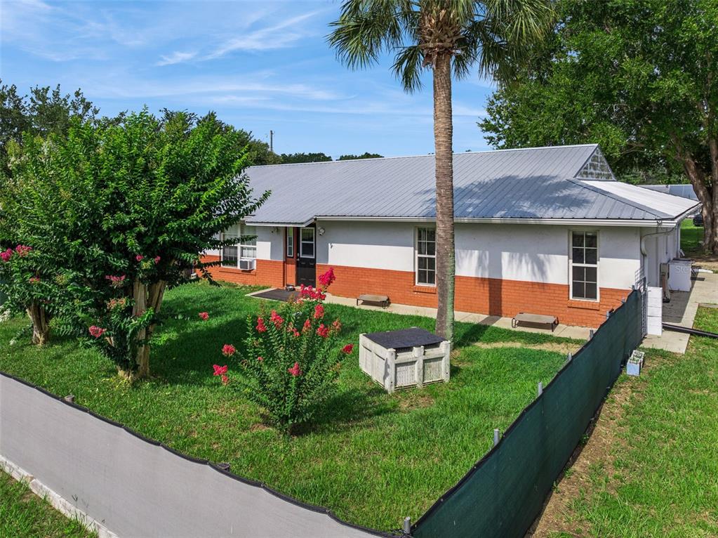 A single-story house with a metal roof and a brick-and-stucco exterior sits behind a fence — 15000 S US HIGHWAY 441 HIGHWAY S, SUMMERFIELD, FL