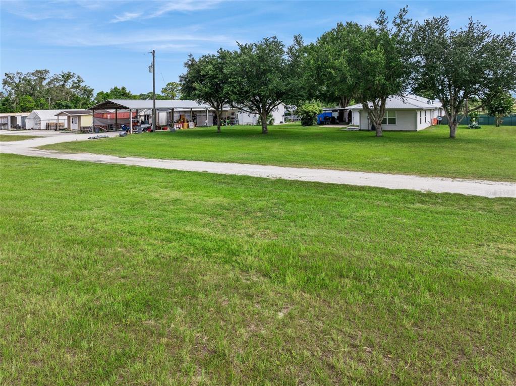 A gravel driveway leads to a house and a large metal carport on a grassy lot — 15000 S US HIGHWAY 441 HIGHWAY S, SUMMERFIELD, FL