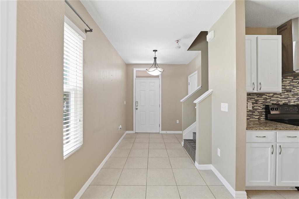 A tiled entryway leads to a white front door with a staircase on the right — 13755 COVEY RUN PLACE, SPRING HILL, FL
