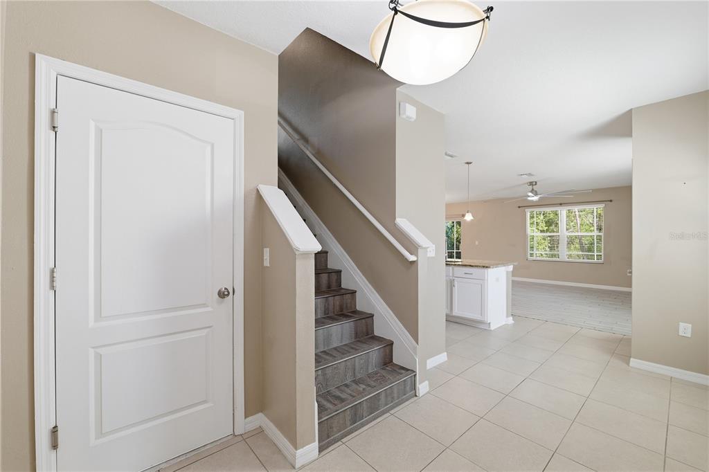 An entryway features a white door, a staircase with wood-look treads, and tile flooring — 13755 COVEY RUN PLACE, SPRING HILL, FL