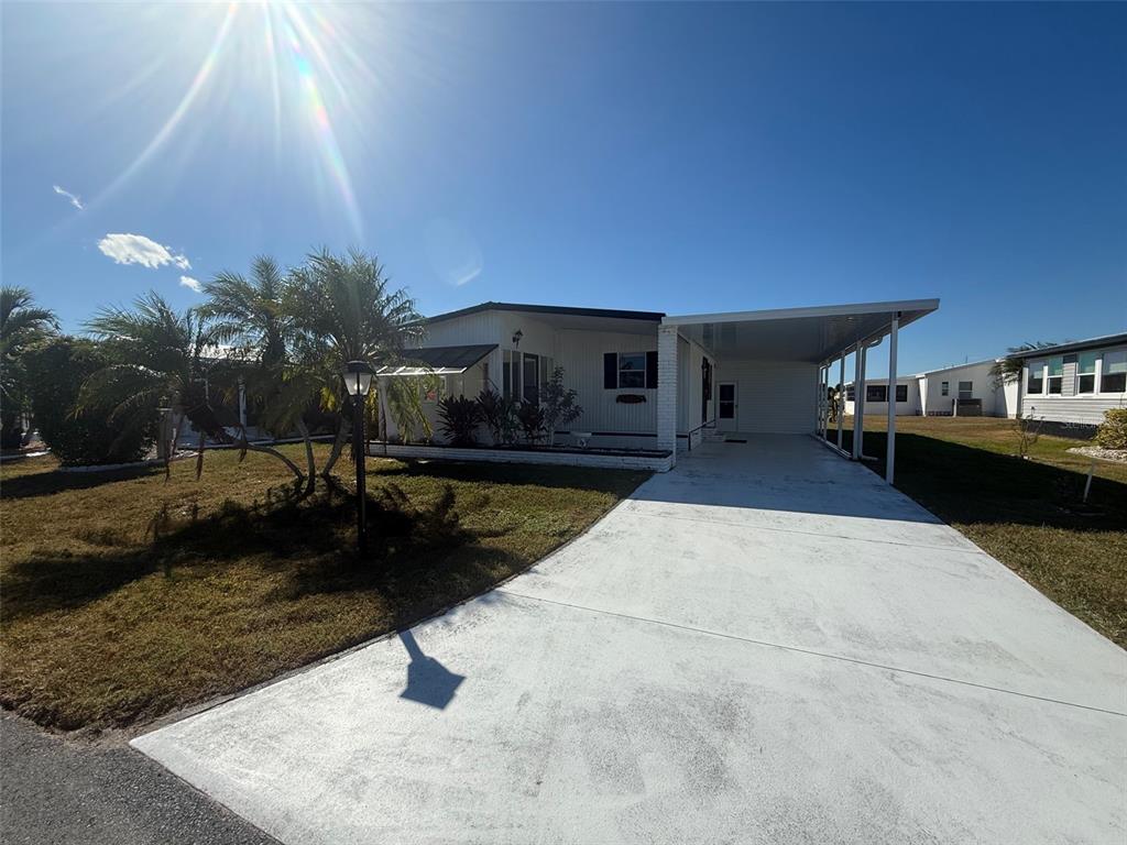 A single-story manufactured home features a white exterior, a concrete driveway, and a covered carport — 731 BLANCA, NORTH PORT, FL
